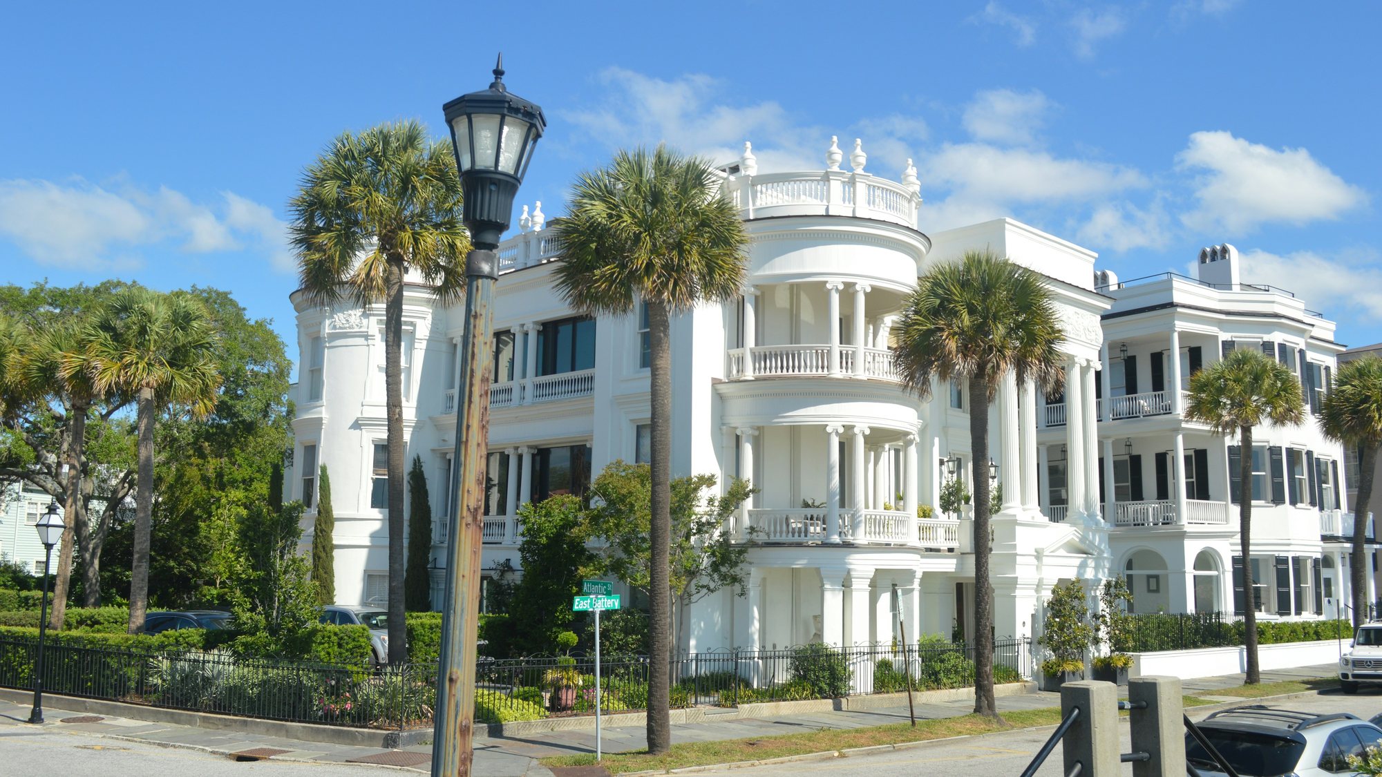 A white historic house with curved balconies and palmettos in Charleston